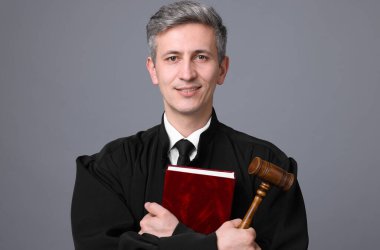 Çekiç ve gri arka plan kitabı ile gülümseyen yargıç