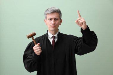 Yeşil arka planda yukarı bakan çekiçli yargıç