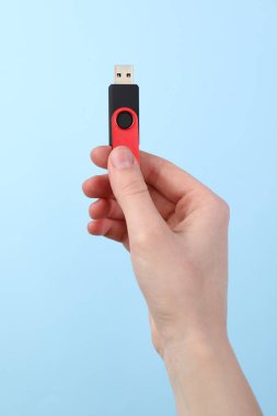 Flaş belleği açık mavi arkaplanda tutan kadın, yakın plan.