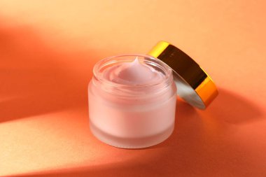 Turuncu arka planda bir kavanoz nemlendirici vücut kremi, yakın plan.