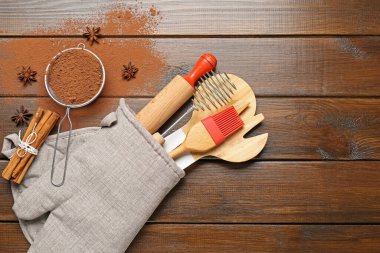 Farklı mutfak aletleri fırın eldivenlerinde, kakao tozu, tarçın ve anason yıldızları tahta masada, düz yerde