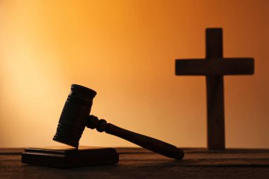 Hakimin tokmağının silüeti ve ahşap masanın üzerinde soluk turuncu eğimli arka plan, yakın plan