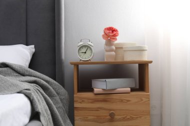 Alarm saati, kitaplar ve evin içinde yatağın yanındaki dekorun olduğu komodinin yanında. İç tasarım