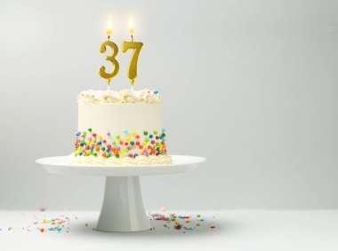 Yanan mumlar ve hafif arka planda serpiştirilmiş şekerlemelerle nefis bir pasta, yazı için boşluk. 37. yaş günü veya diğer özel günler