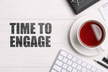 Harekete geçme zamanı. Bir fincan çay, bilgisayar klavyesi ve beyaz ahşap masa üzerindeki kırtasiye malzemesi.