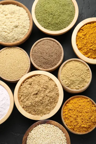 Koyu dokulu masada, düz bir zeminde, kaselerdeki farklı süper yiyecek tozları.