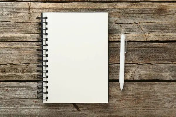 Defter ve kalem ahşap masada, düz yatıyordu.