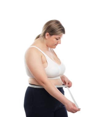 Kilo kaybı. Artı, beyaz arka planda bantla bel ölçüsü ölçen bir kadın.