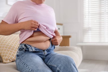 Evde göbeği aşırı yağlı bir kadın, yakın plan. Aşırı kilolu