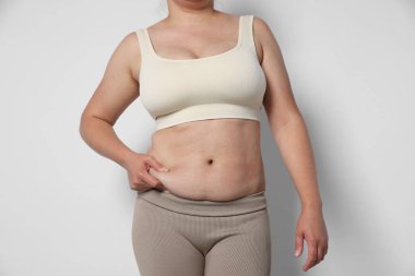 Hafif arka planda aşırı göbek yağı olan kadın, yakın plan. Aşırı kilolu