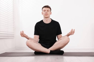 Genç adam evde yoga yapıyor.