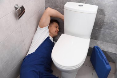 Profesyonel tesisatçı tuvalette klozet tamir ediyor.