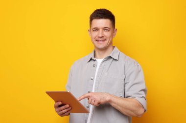 Sarı arka planda modern tablet kullanan bir adam. Metin için boşluk