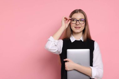 Pembe arka planda dizüstü bilgisayarı olan güzel bir genç kız. Metin için boşluk