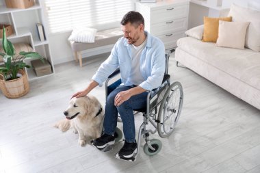 Tekerlekli sandalyedeki adam, hizmetli köpeği evde, yukarıda.