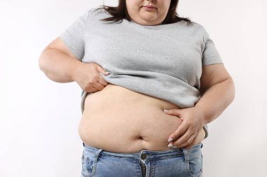 Beyaz arka planda aşırı göbek yağı olan kadın, yakın plan.