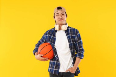 Kulaklıklı ve turuncu arka planda basketbol topu olan bir öğrenci.