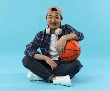 Kulaklıklı öğrenci ve açık mavi arka planda basketbol topu.