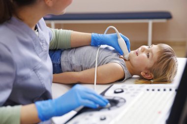 Sonograf, klinikte küçük kızın tiroid bezini ultrason muayenesi yapıyor.