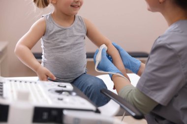 Sonograf, klinikte küçük bir kızın kolunun ultrason muayenesi yapıyor.