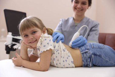 Küçük kızın böbrek ultrasonu muayenesini klinikte yapan sonograf.