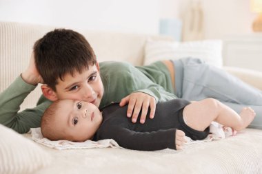 Evdeki kanepede oturan sevimli küçük kardeşler.