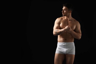 Siyah arka planda beyaz iç çamaşırlı genç bir adam. Metin için boşluk