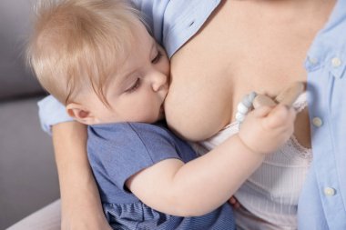 Anne küçük bebeğini evde emziriyor, yakın plan.