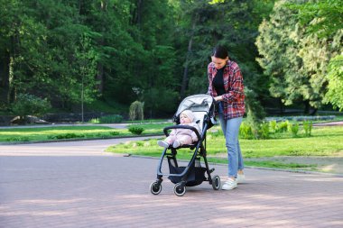 Anne bebeğiyle parkta bebek arabasında yürüyor. Metin için boşluk
