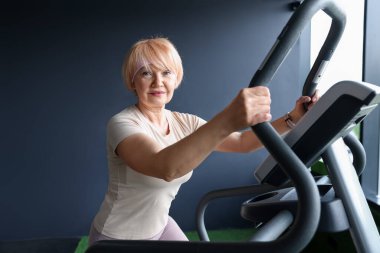 Son sınıf kadın spor salonunda eliptik makine eğitimi alıyor.