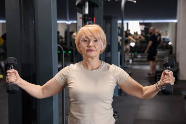 Üst düzey kadın spor salonunda dumbbells ile eğitim