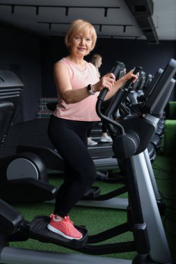 Son sınıf kadın spor salonunda eliptik makine eğitimi alıyor.