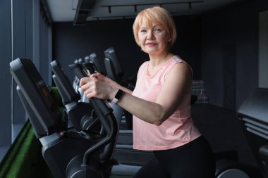 Son sınıf kadın spor salonunda eliptik makine eğitimi alıyor.