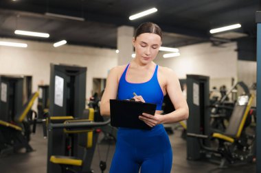 Spor salonunda panosu olan profesyonel kişisel antrenör.