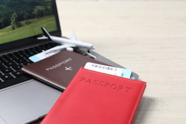 Pasaportlar, uçuş biletleri, uçak modeli ve laptop ahşap masada, yakın plan.