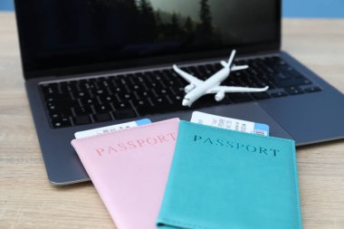 Pasaportlar, uçuş biletleri, uçak modeli ve laptop ahşap masada, yakın plan.