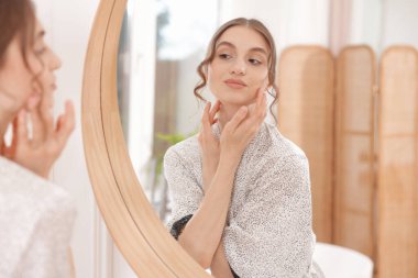 Güzel bir kadın aynada kendine bakıyor.