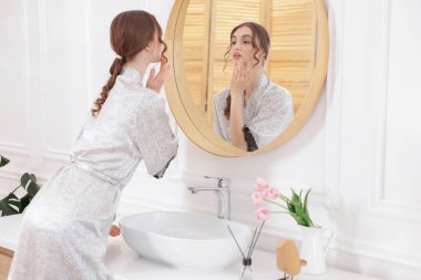 Güzel bir kadın aynada kendine bakıyor.