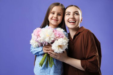 Anne ve kızı mor arka planda bir buket güzel şakayıkla, mesaj atmak için yer var.