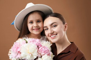 Anne ve kızı kahverengi arka planda bir buket güzel şakayıkla