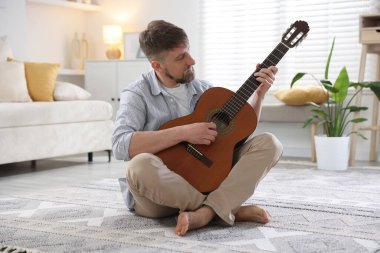 Evde gitar çalan adam.