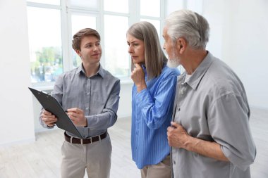 Evdeki çiftle çalışan panolu bir emlakçı.