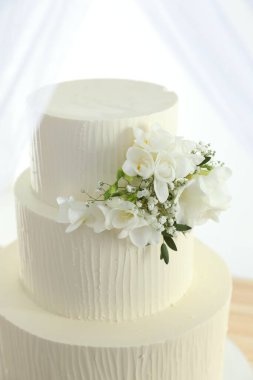 Çiçekli nefis düğün pastası ve beyaz arka planda perdeler, yakın plan.