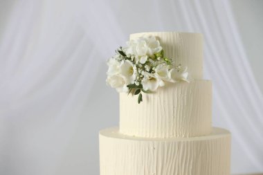 Çiçek desenli nefis düğün pastası ve beyaz arka planda perdeler, yakın plan. Metin için boşluk