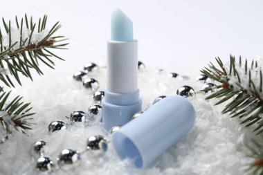 Nemlendirici dudak kremi, Noel dekorasyonu ve yapay kar üzerindeki köknar ağacı dalları, yakın plan. Kış bakımı