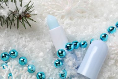 Nemlendirici dudak kremi, Noel dekorasyonu ve yapay kar üzerinde köknar ağacı dalları. Kış bakımı