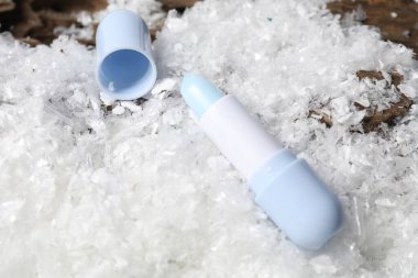 Yapay karda nemlendirici dudak kremi, yakın plan. Kış bakımı