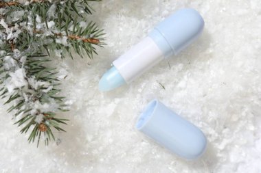 Nemlendirici dudak kremi ve yapay kar üzerinde köknar ağacı dalları. Kış bakımı