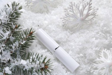 Nemlendirici dudak kremi, Noel dekorasyonu ve yapay kar üzerinde köknar ağacı dalları. Kış bakımı