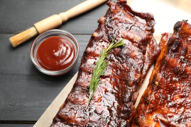 Biberiyeli domuz pirzolası ve siyah ahşap masanın üstünde sos.